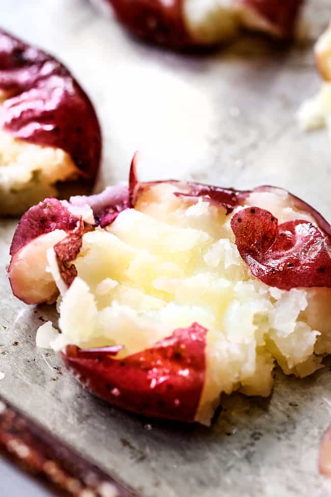 showing how to make smashed potatoes by lining red potatoes on a baking sheet after being smashed
