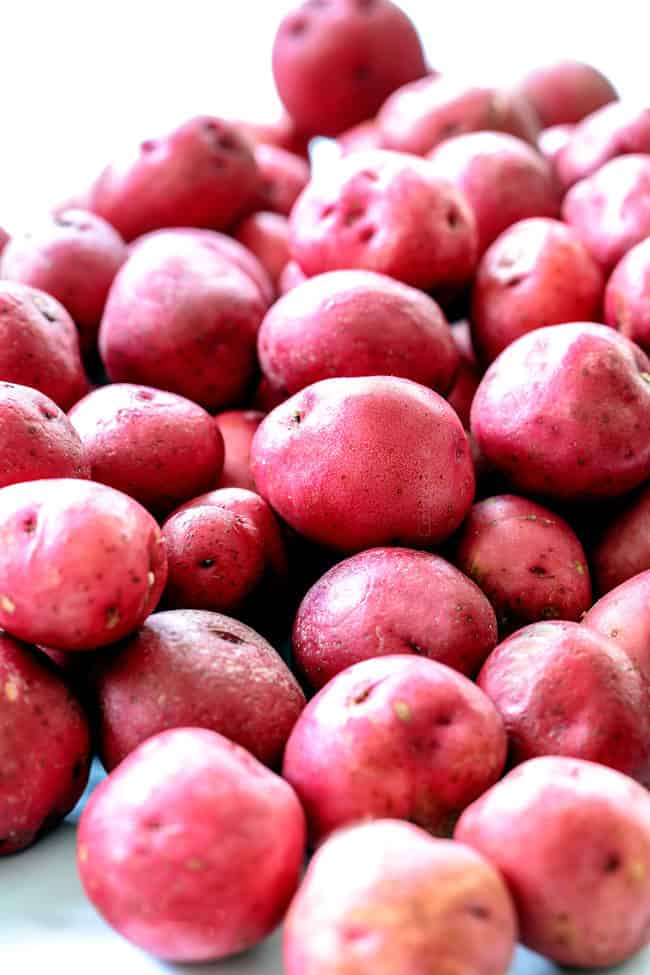 showing how to make smashed potatoes by washing red potatoes