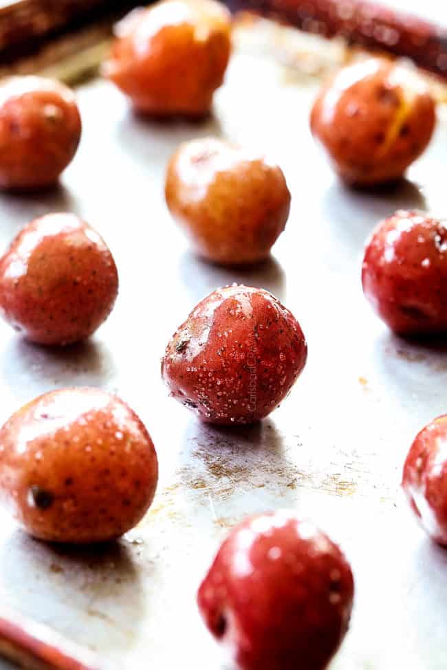 showing how to make smashed potatoes by adding red potatoes to a baking sheet