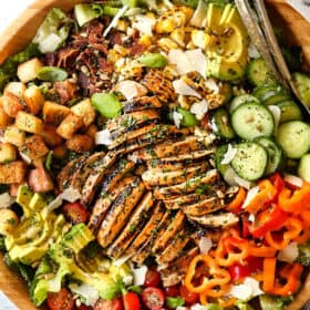 top view of Chicken Caesar Salad in a wood bowl with croutons, grilled chicken and Caesar dressig