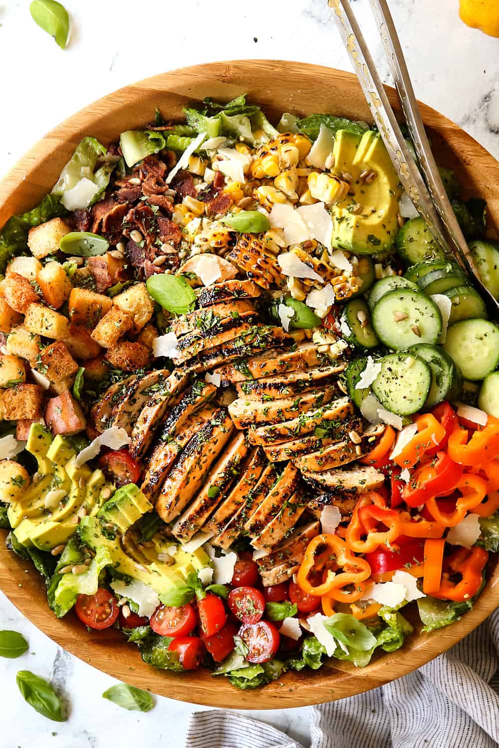 top view of Chicken Caesar Salad in a wood bowl with croutons, grilled chicken and Caesar dressig