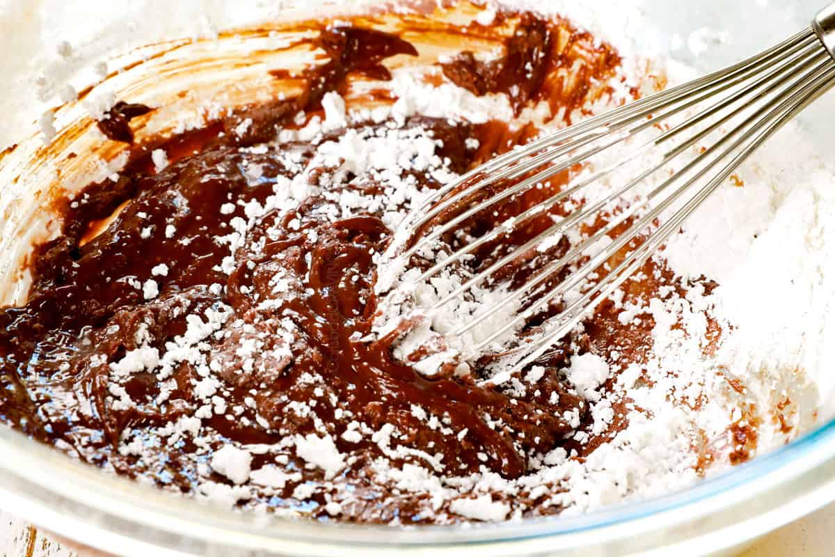 showing how to make chocolate lava cake recipe by whisking powdered sugar into melted chocolate and butter