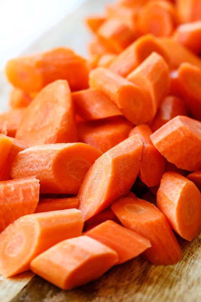 showing how to make glazed carrots by chopping carrots on a cutting wooden board