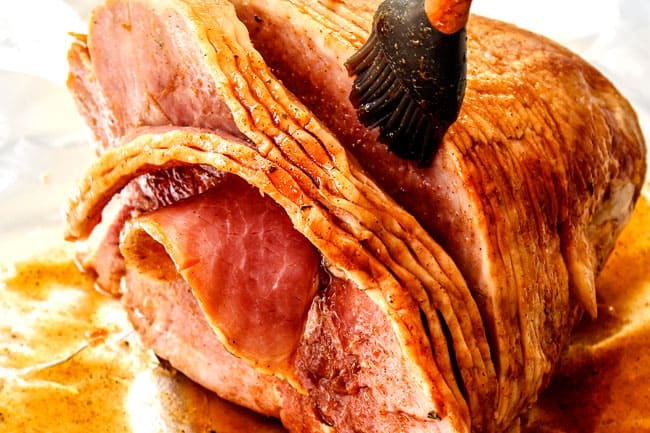 showing how to make spiral ham with pineapple ham glaze by brushing brown sugar pineapple ham glaze all over over spiral ham