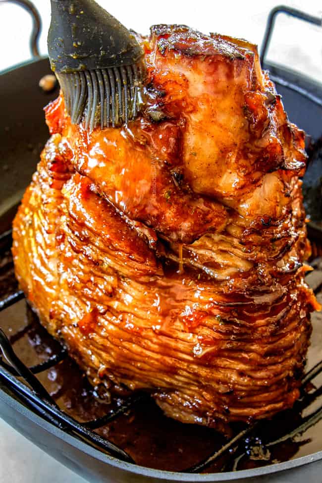 showing how to make honey baked ham by glazing ham with honey glaze