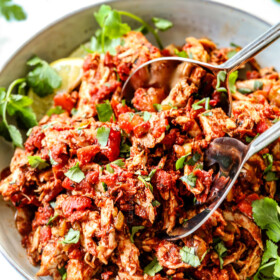 two tongs picking up chipotle Mexican chicken