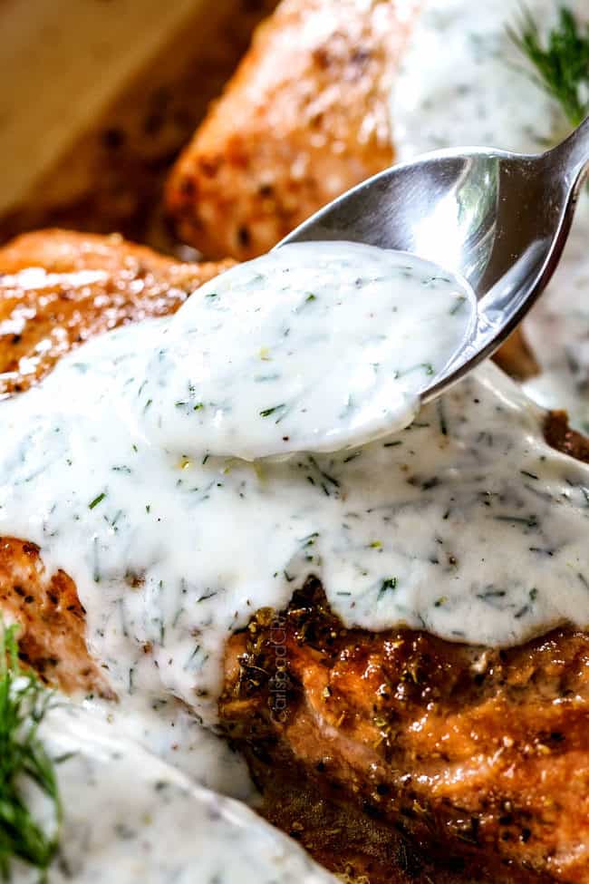 spooning dill sauce over salmon with a spoon