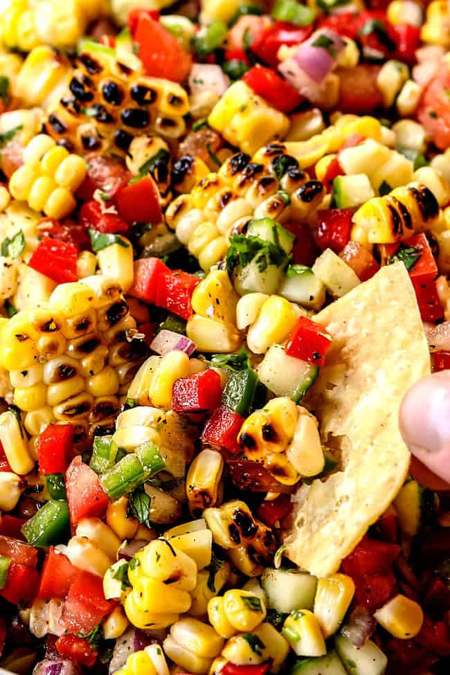 up close of scooping easy corn salsa recipe with a tortilla chip