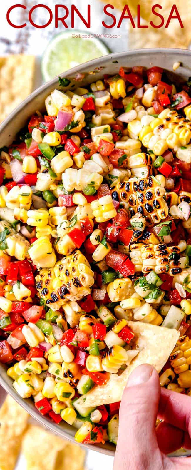 top view of fresh corn salsa in a bowl with a holding a chip