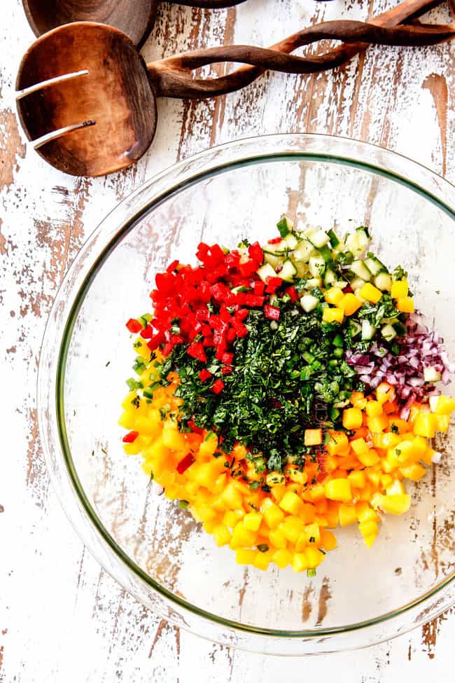 showing how to make mango salsa with top view of bowl with mangos, red onions, bell peppers, cilantro and lime