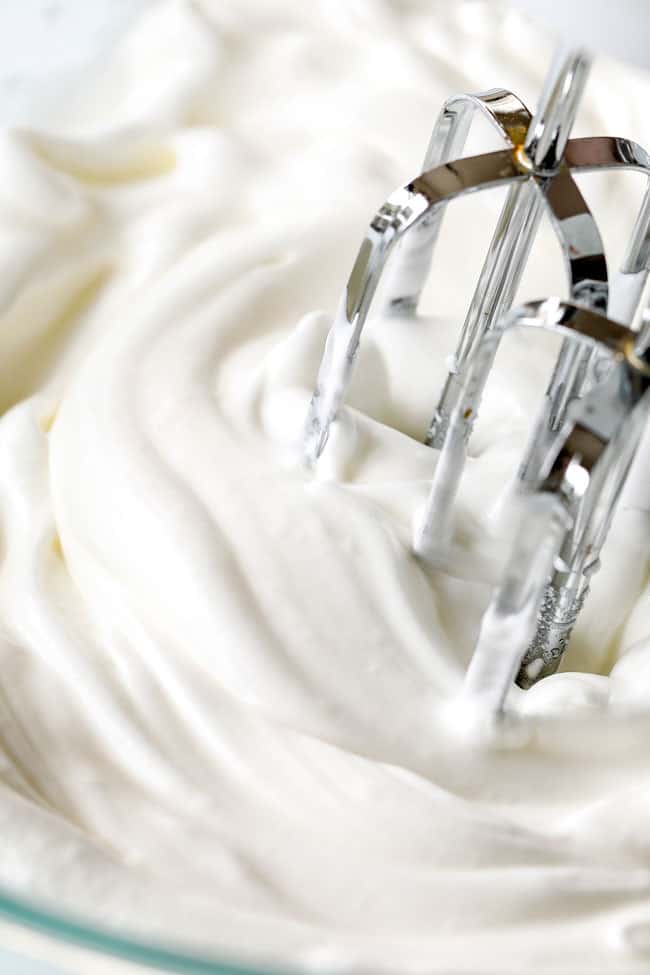 showing how to make strawberry shortcake cake by whipping egg whites until soft peaks form