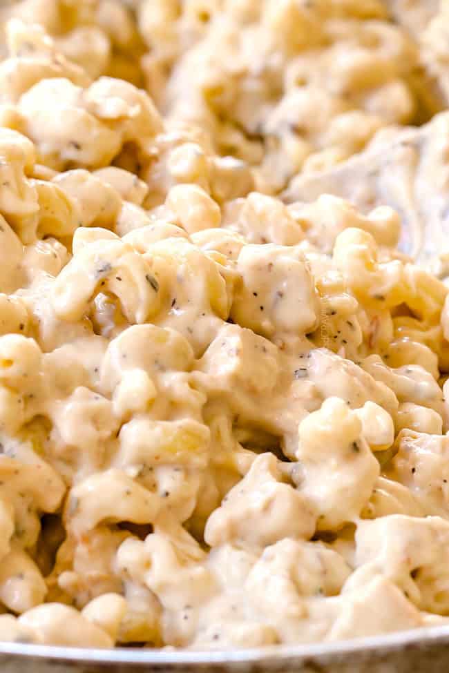 showing how to make Chicken Alfredo Bake by stirring chicken and pasta into sauce until well combined