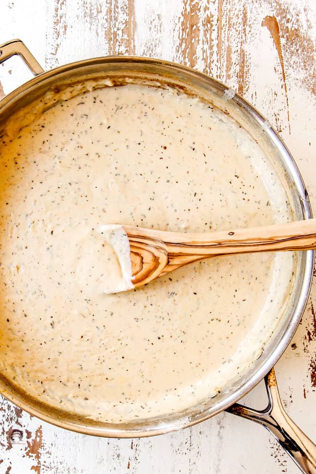 showing how to make Chicken Alfredo Bake by adding heavy cream to garlic in a skillet