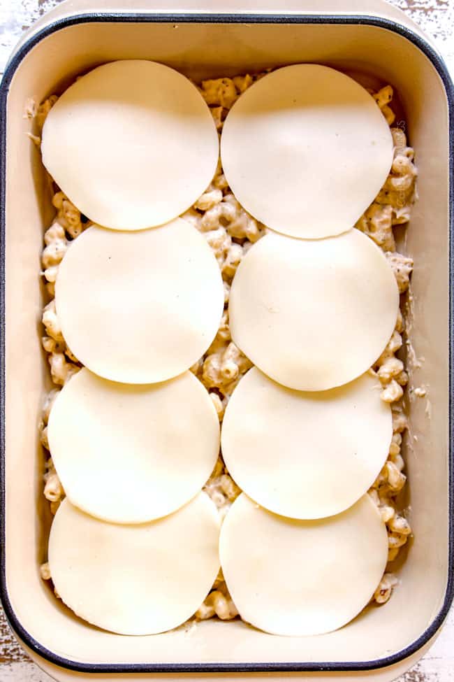 showing how to make Chicken Alfredo Bake by adding a layer of provolone over pasta