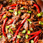 top view of crispy Szechuan beef in a work with peppers
