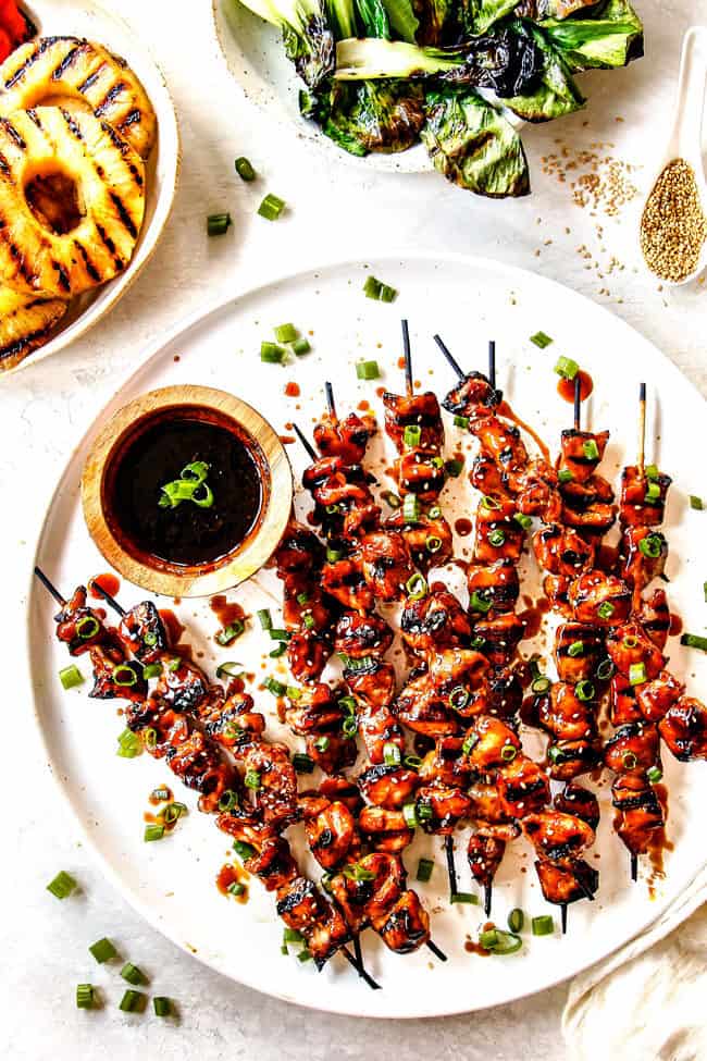 top view of grilled momo yakitori on a white platter with a side of yakitori sauce