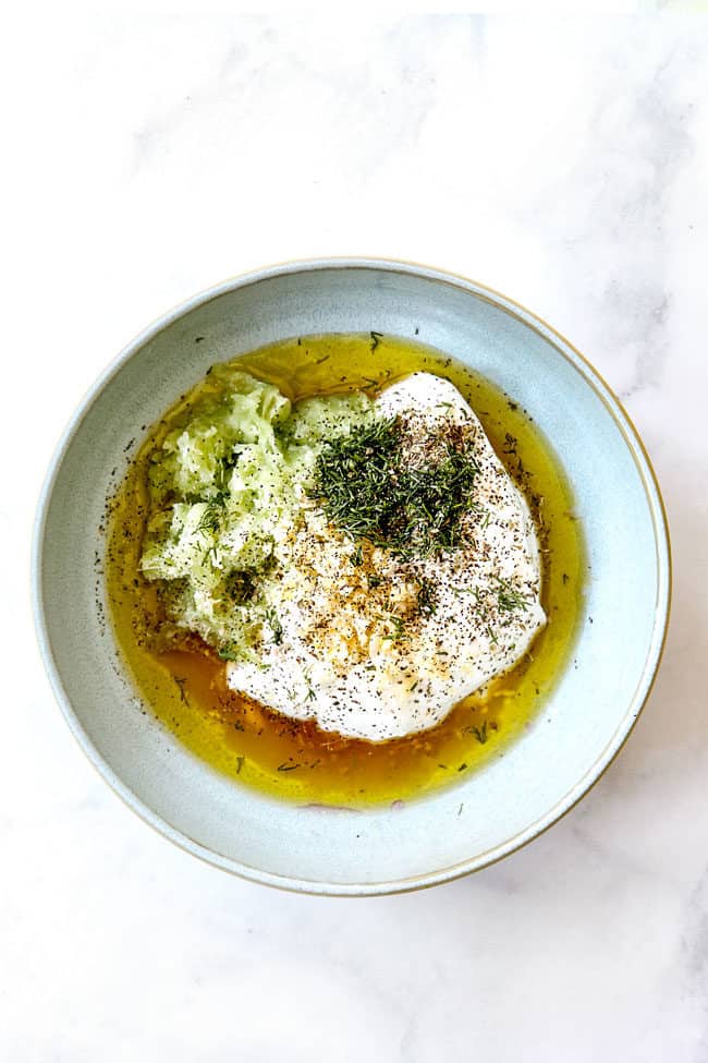 showing how to make chicken gyro recipe by adding tzatziki ingredients to a bowl