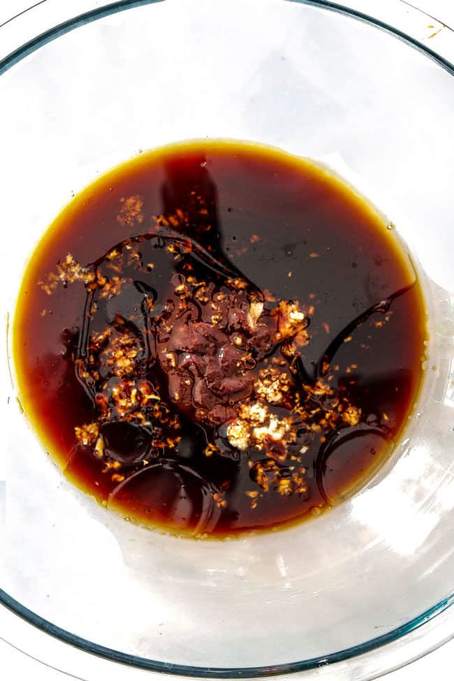 showing how to make Korean Chicken by whisking soy sauce, garlic, ginger, gochujang, honey together