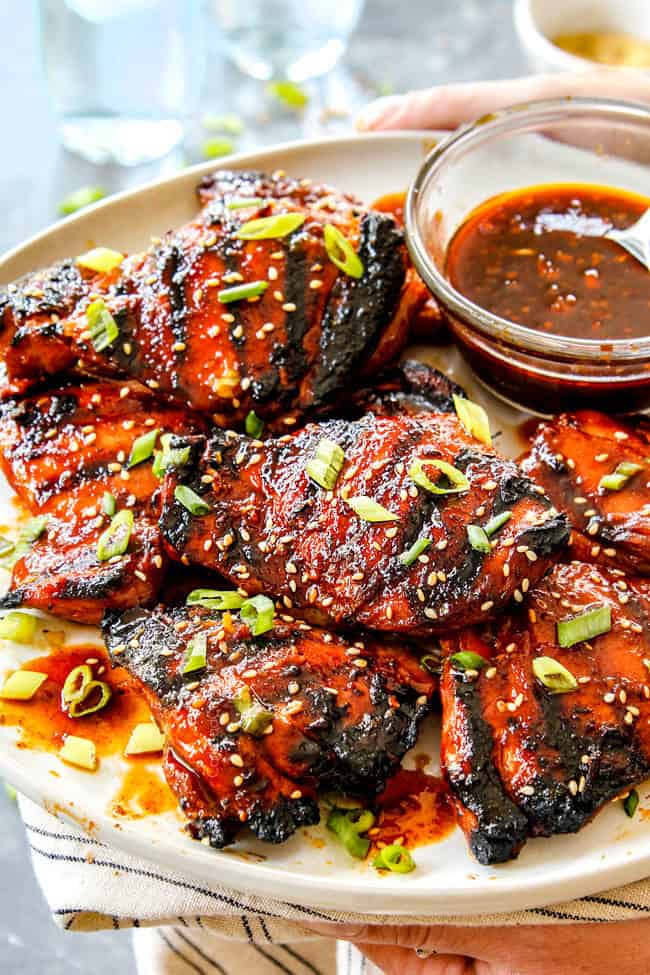 two hands holding a platter of Korean Chicken with gochujang