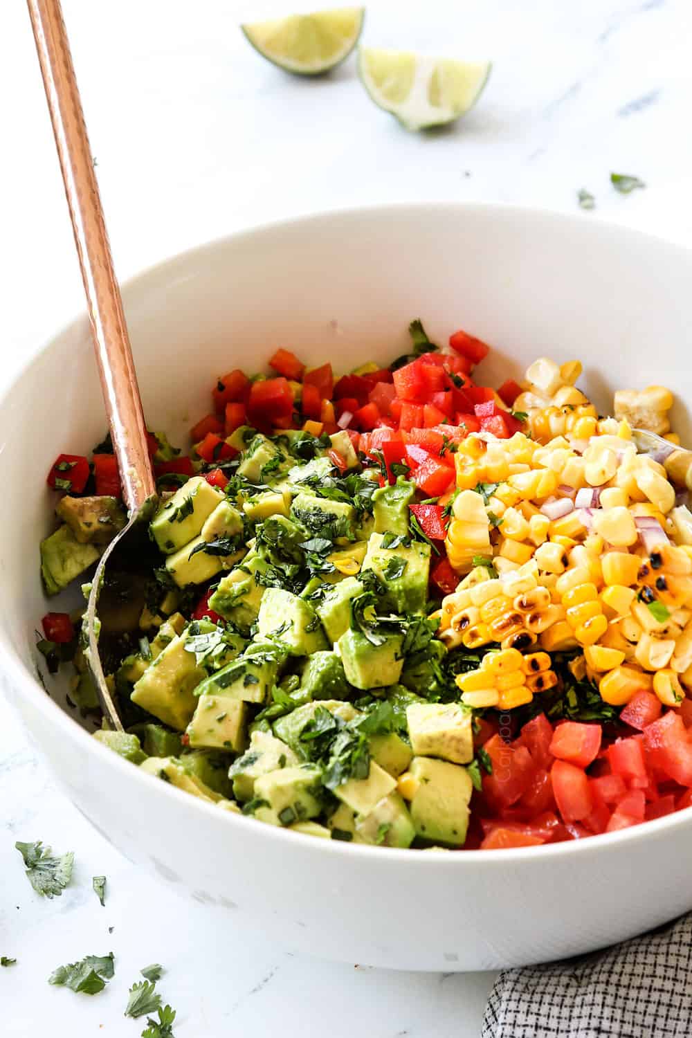 two serving spoon stirring avocado salsa recipe