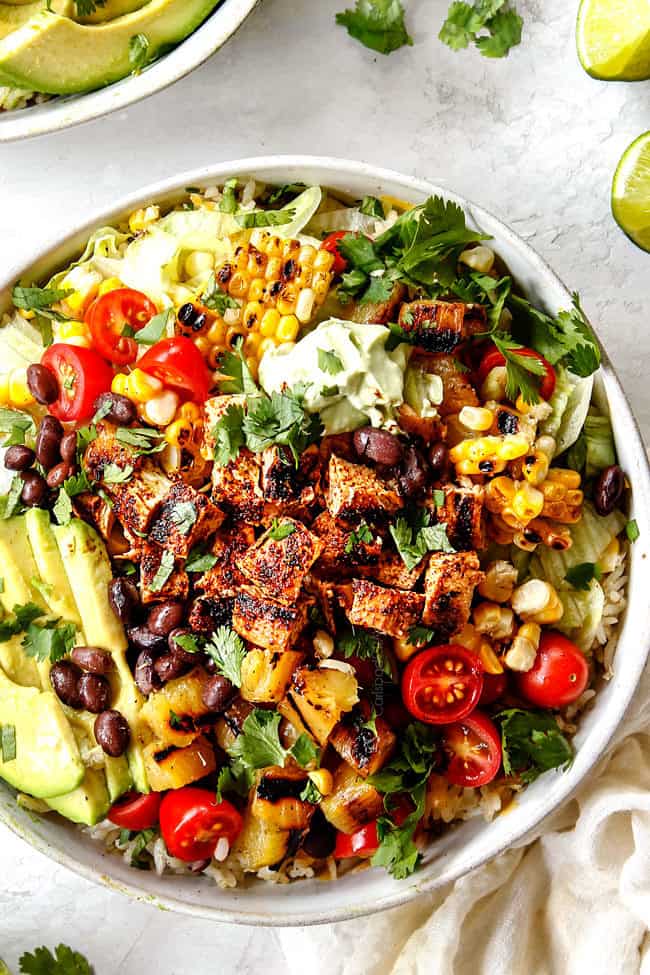 top view of burrito bowls with chicken, rice, corn, avocados, salsa