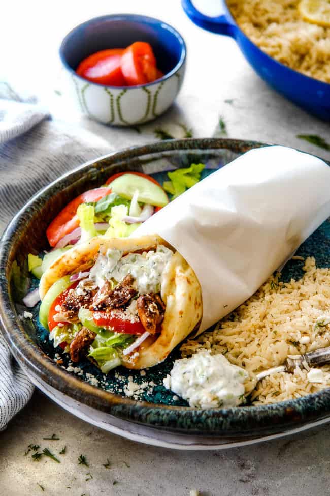 showing what to serve with chicken gyros with a gyro on a plate with Greek rice and salad