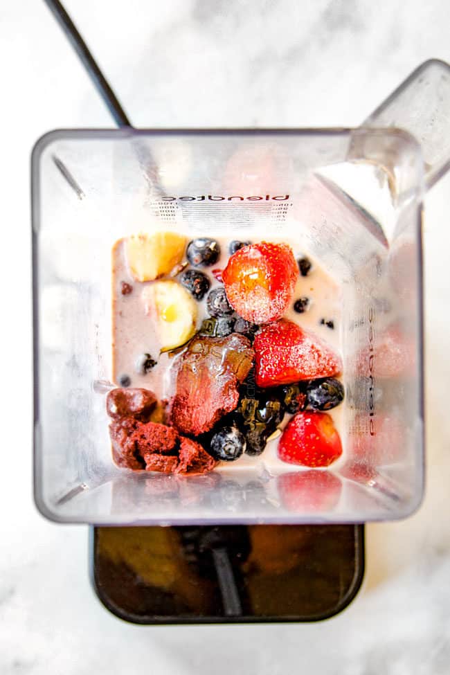 showing how to make acai bowls by adding bananas, strawberries, blueberries and milk to blender
