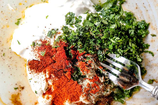 showing how to make elote by adding mayonnaise, Mexican crema, cilantro, chiili powder, lime juice and lime zest to a plate