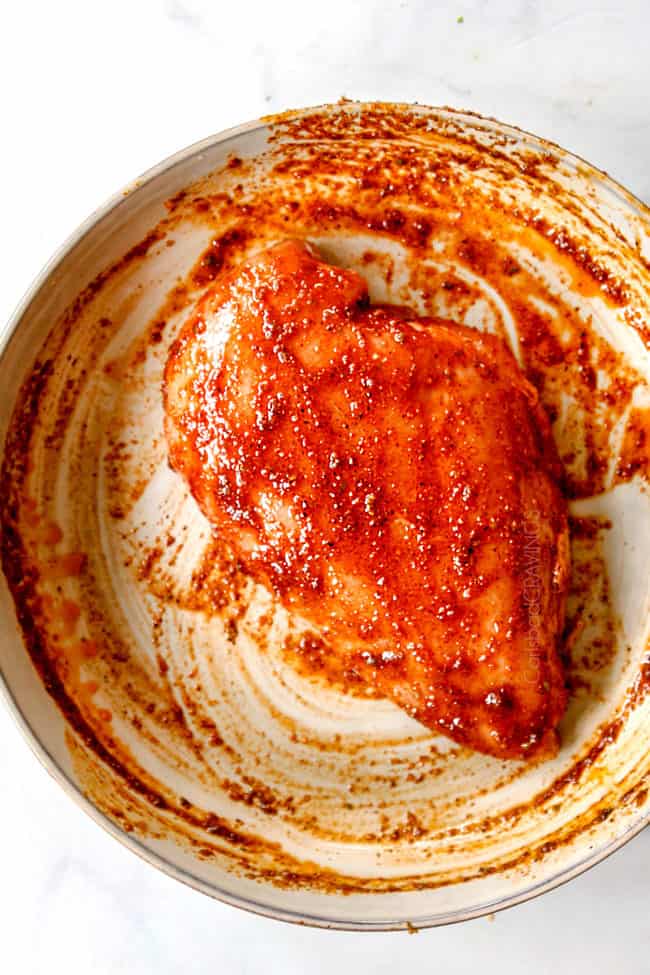 showing how to make fiesta lime chicken by coating chicken in wet rub in a bowl