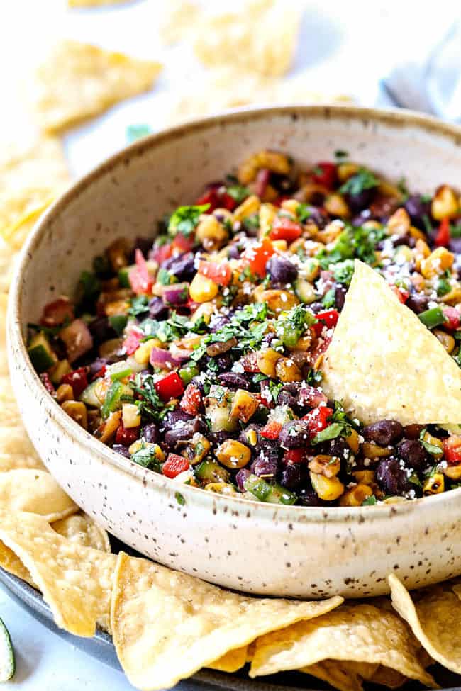 black bean corn salsa in a serving bowl with a chip dipping into it