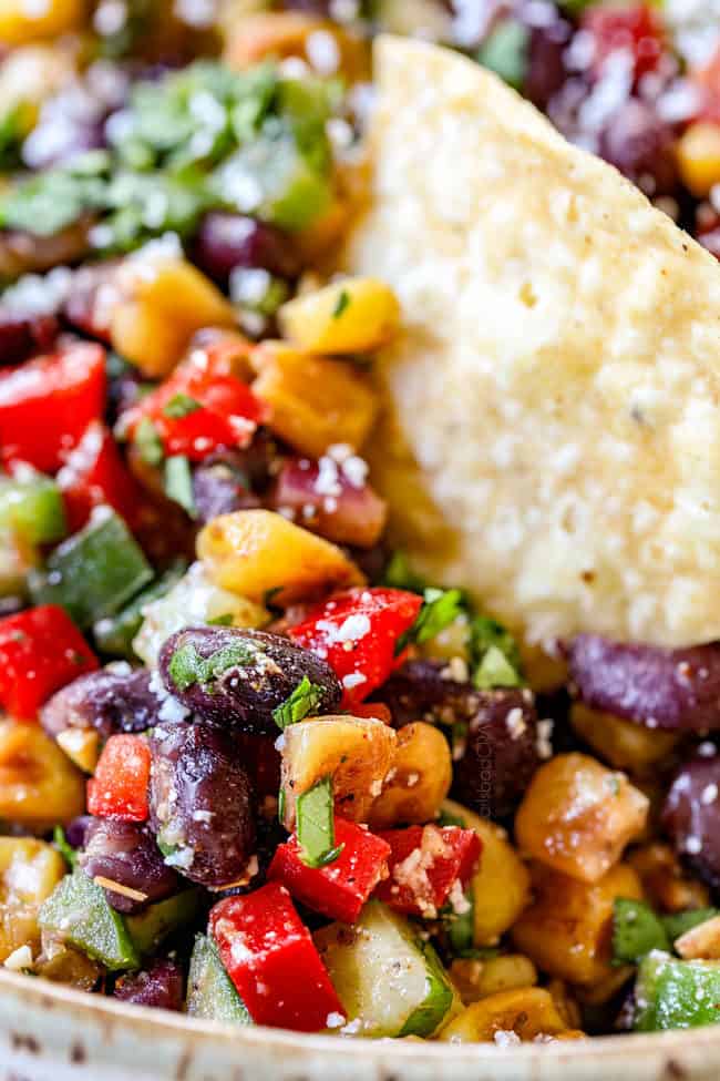 up close of a tortilla chip dipping into black bean corn salsa recipe