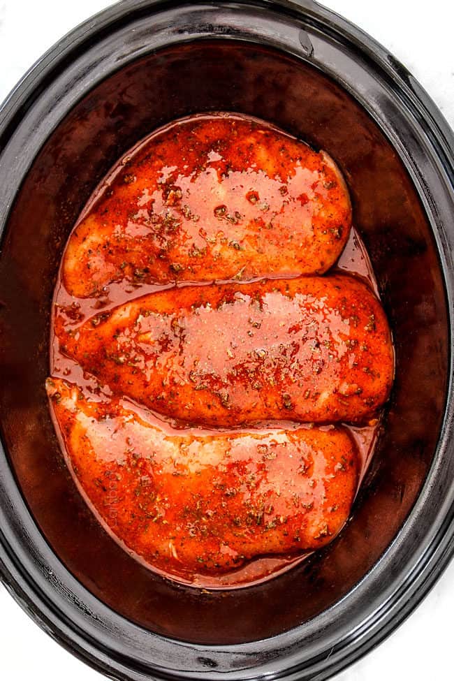 showing how to make crockpot buffalo chicken by adding chicken and buffalo sauce to a slow ooker