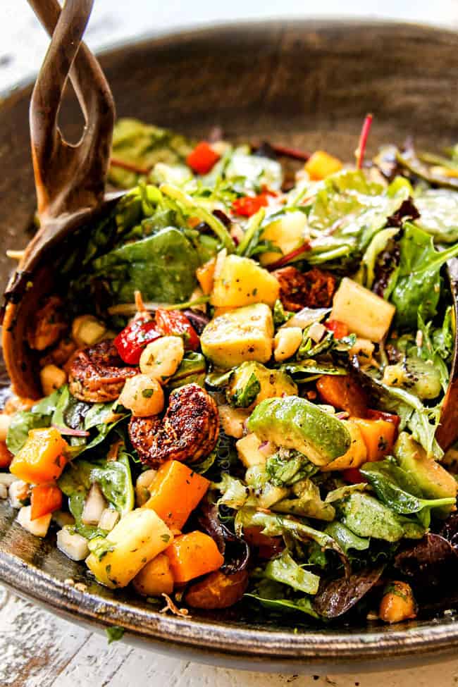 showing how to make shrimp and avocado salad recipe by tossing salad with dressing ingredients in a bowl