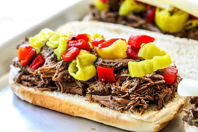 showing how to make slow cooker Italian Beef sandwiches by layering Italian Beef recipe with pepperoncini and roasted red bell peppers