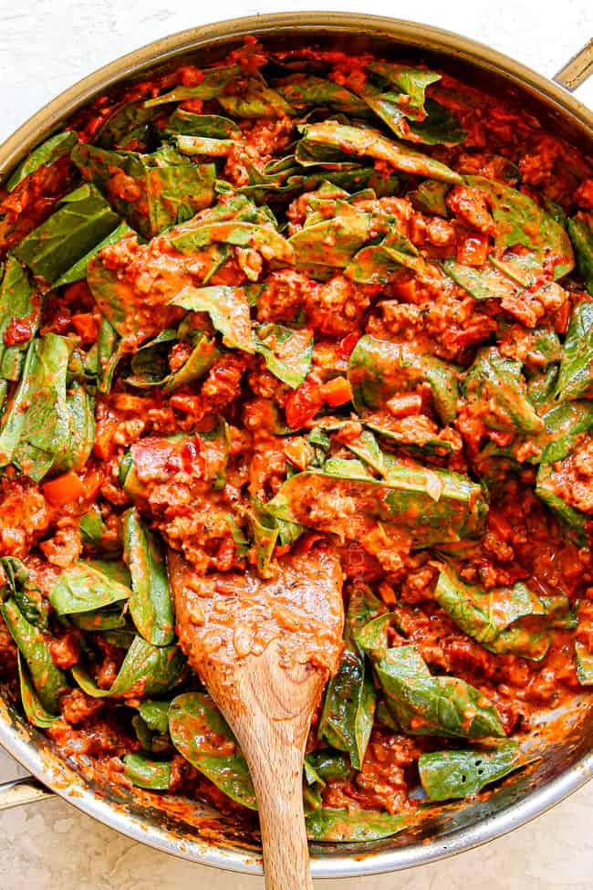 showing how to make rigatoni recipe by stirring in spinach