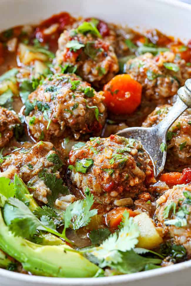 up close of a spoon scooping up a meatball of Albondigas Soup