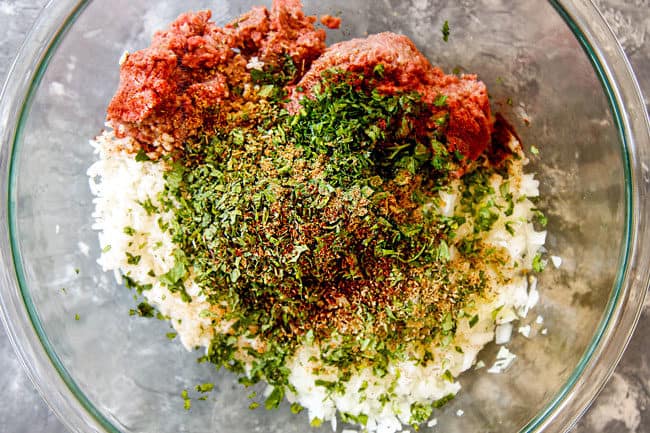 showing how to make meatballs for Albondigas Soup by adding hamburger, pork, onions, rice, garlic, cilantro, mint, oregano and parsley to a bowl