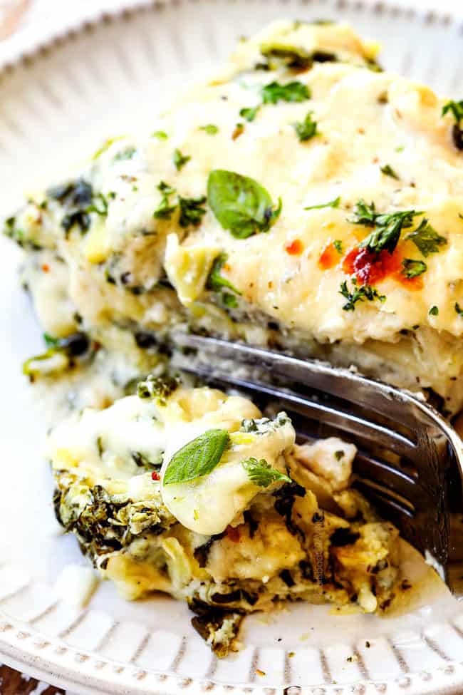 up close of a fork picking up chicken alfredo lasagna