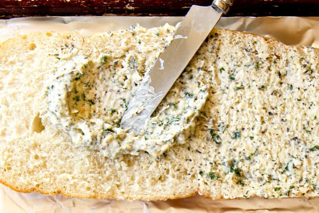 up close showing how to make garlic bread recipe by spreading garlic butter spread with a knife on bread