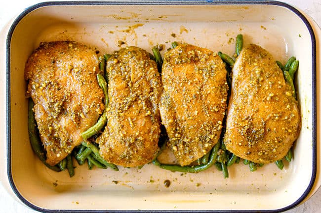 showing how to make pesto chicken bake by adding chicken on top of green beans