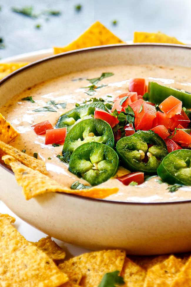 showing how to garnish White Queso Dip (Queso Blanco) by topping with jalapenos, tomatoes and cilantro