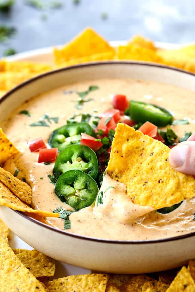 up close of a chip dipping into white queso dip (queso blanco)