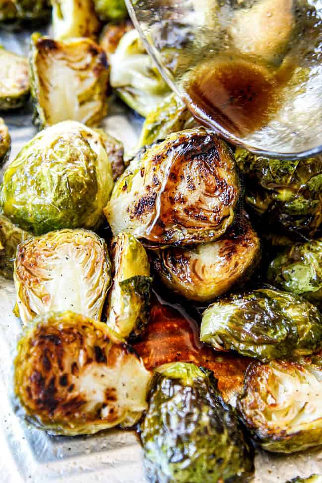 showing how to roast Brussels Sprouts by pouring balsamic over Roasted Brussels Sprouts