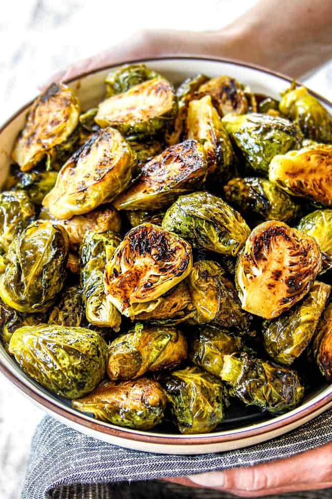 up close of holding a bowl of baked Brussels Sprouts