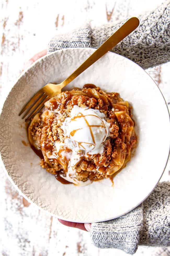 top view of two hands holding a bowl of best apple crisp recipe with oatmeal