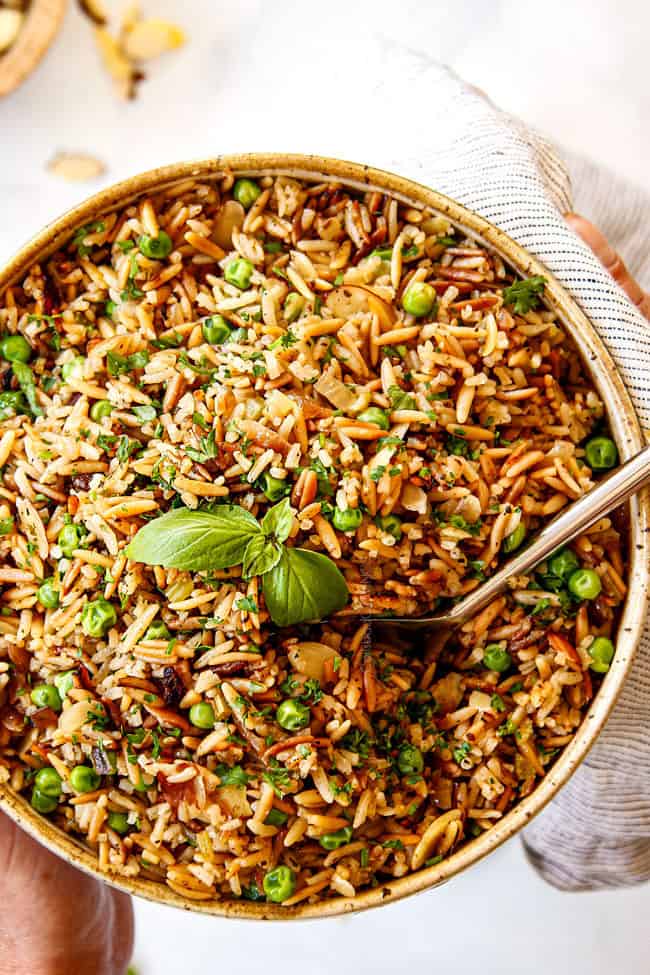 two hands holding a bowl of Rice Pilaf recipe with orzo