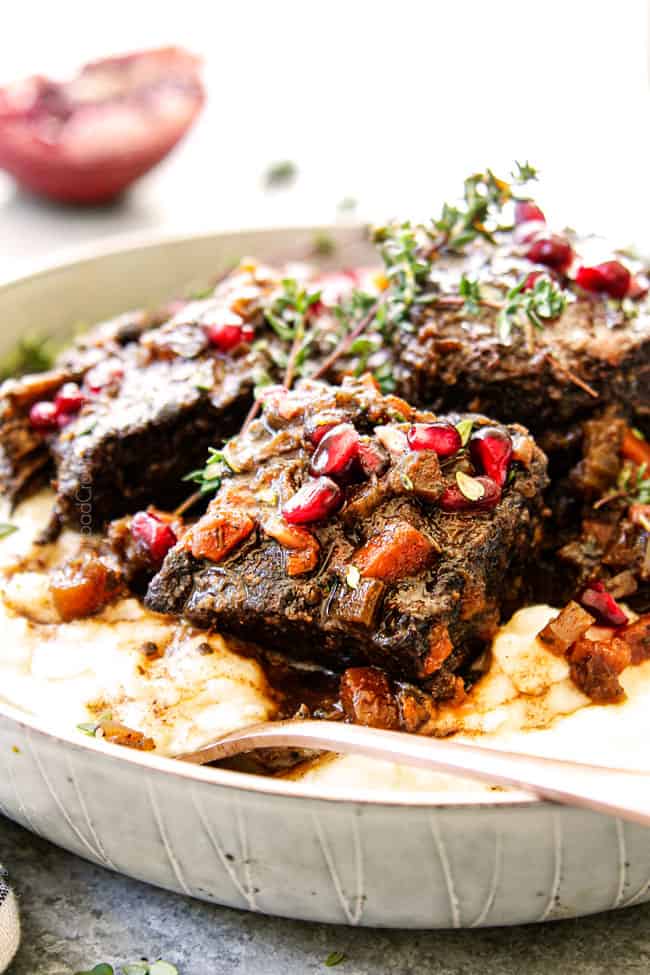 up close of beef short ribs recipe in a white bowl garnished with thyme