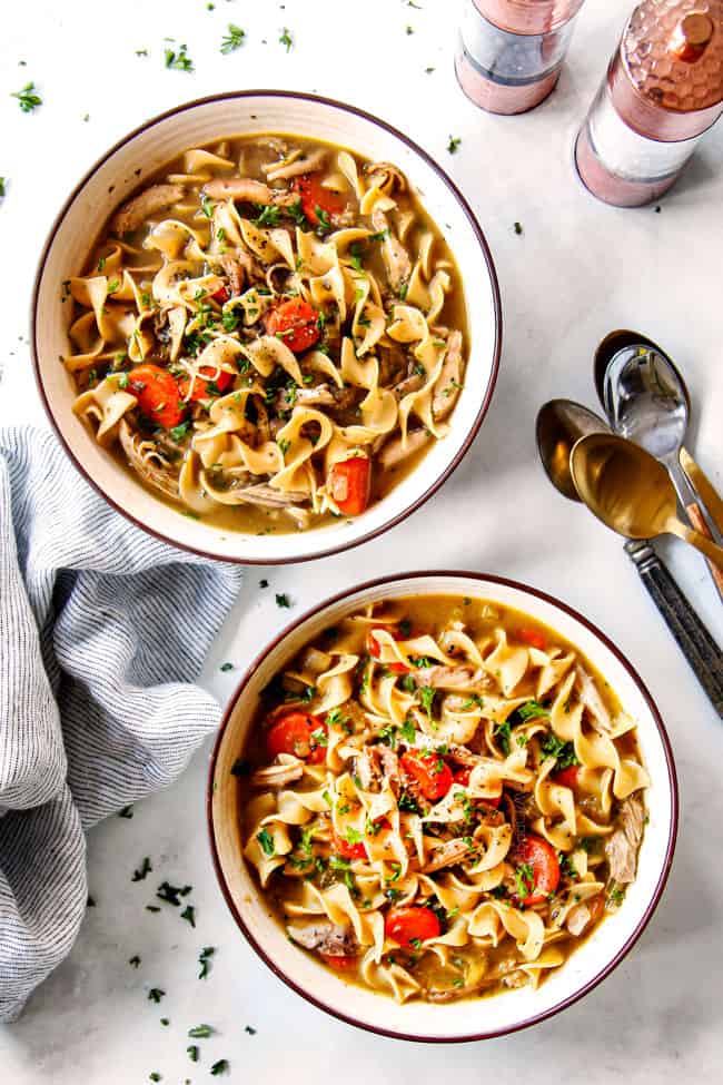 showing how to serve best chicken noodle soup recipe by dividing into bowls and garnishing with parsley