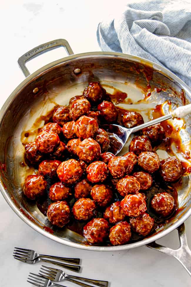 showing how to make cocktail meatball recipe by tossing meatballs with sauce in a skillet 
