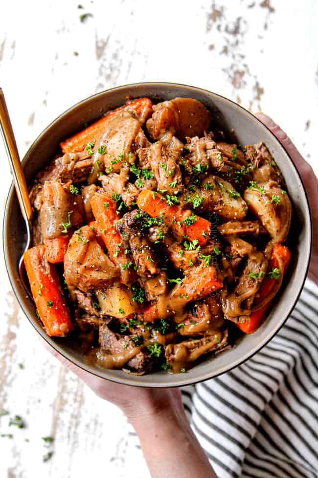 showing how to season the best crock pot roast with basil, thyme, oregano, salt and pepper